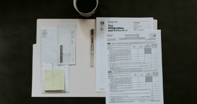 Tax forms, a pen, and a coffee mug on a dark desk